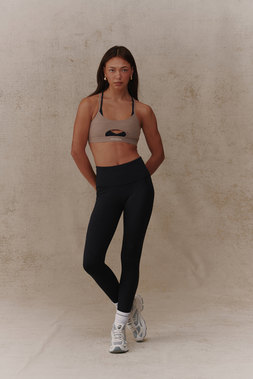 Woman wearing the Antidote Balance Sports Bra in Sand + Nero, front view