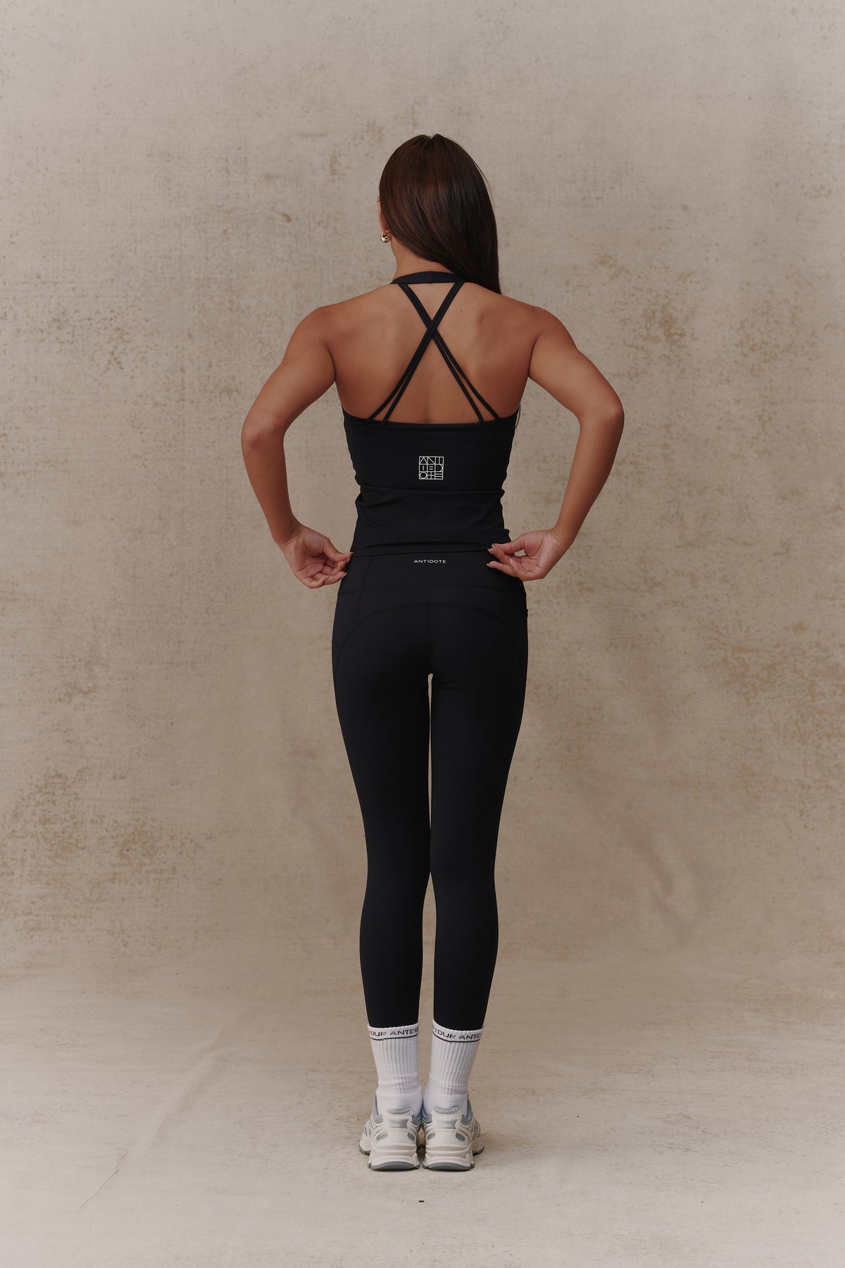 Woman wearing the Antidote Halter Neck Flow top in Black Beauty, back view