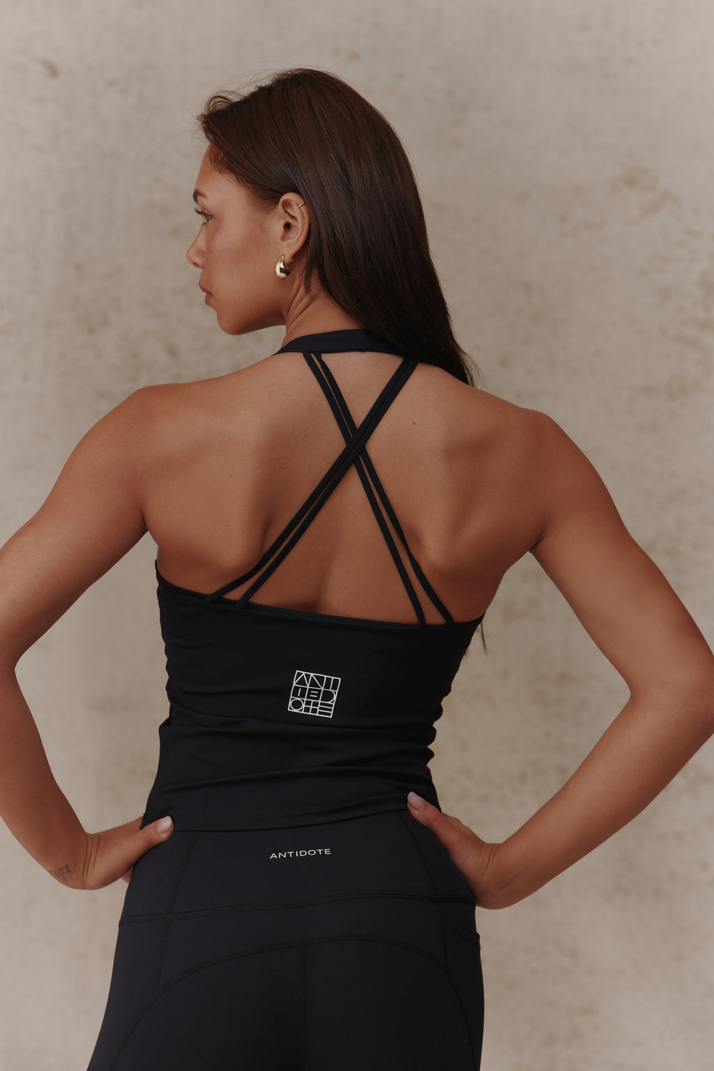 Woman wearing the Antidote Halter Neck Flow top in Black Beauty, close-up of the criss-cross back