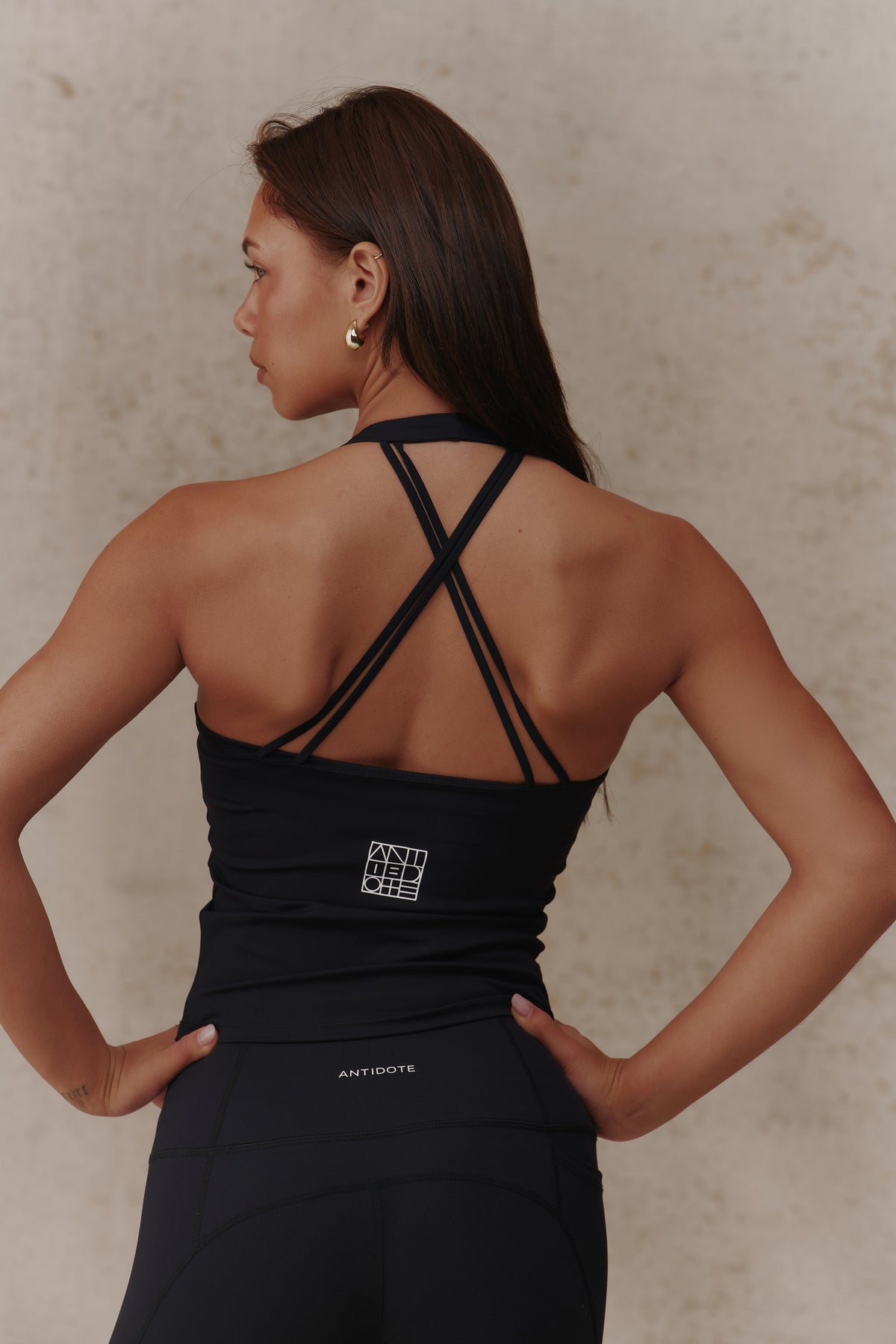 Woman wearing the Antidote Halter Neck Flow top in Black Beauty, close-up of the criss-cross back