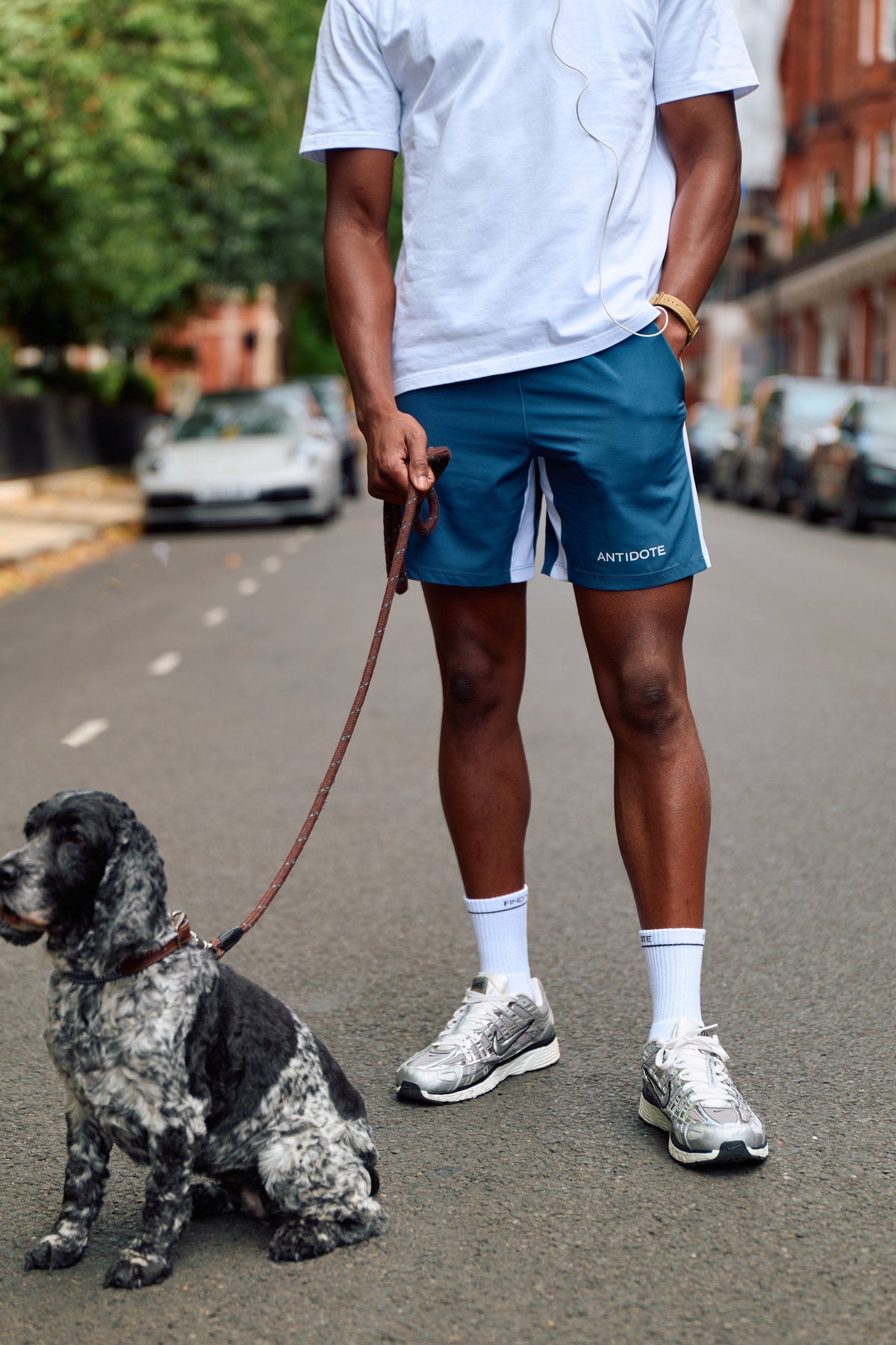 Man wearing the Antidote Motion Men's Shorts 7 inch, walking a dog