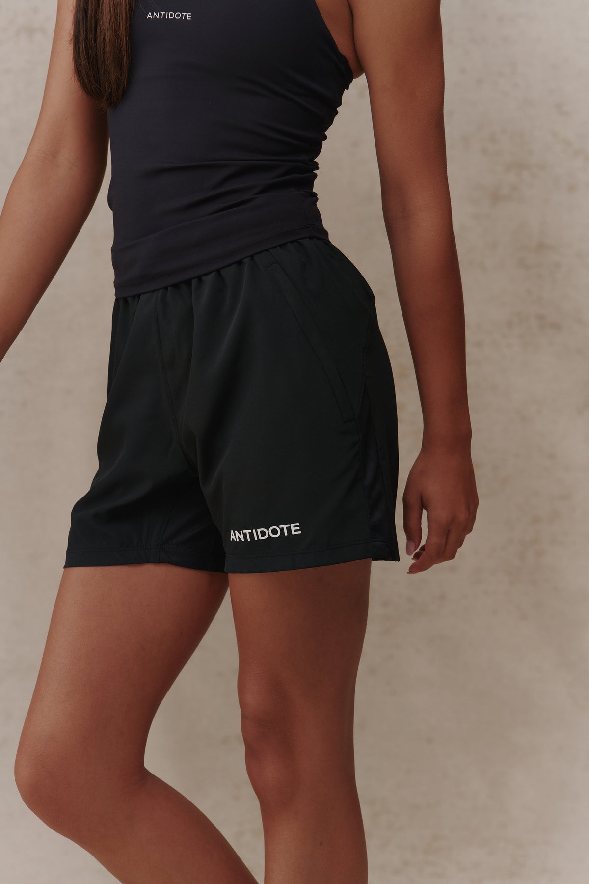 Woman wearing the Antidote Women's Motion Shorts in Noir, close-up side view