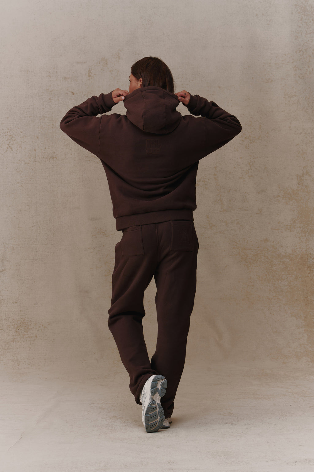 Woman wearing the Antidote Recovery Hoodie in Ganache, back view